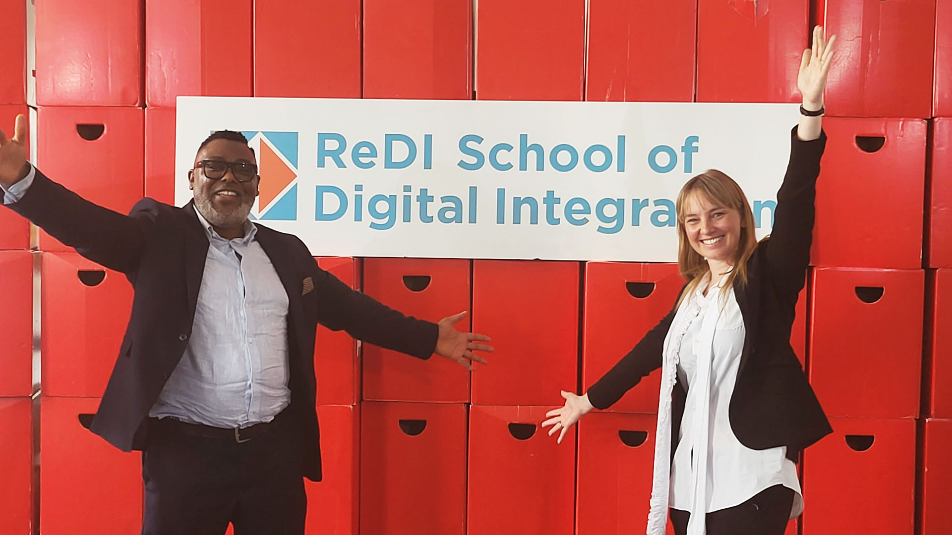 Two happy people in front of a sign.