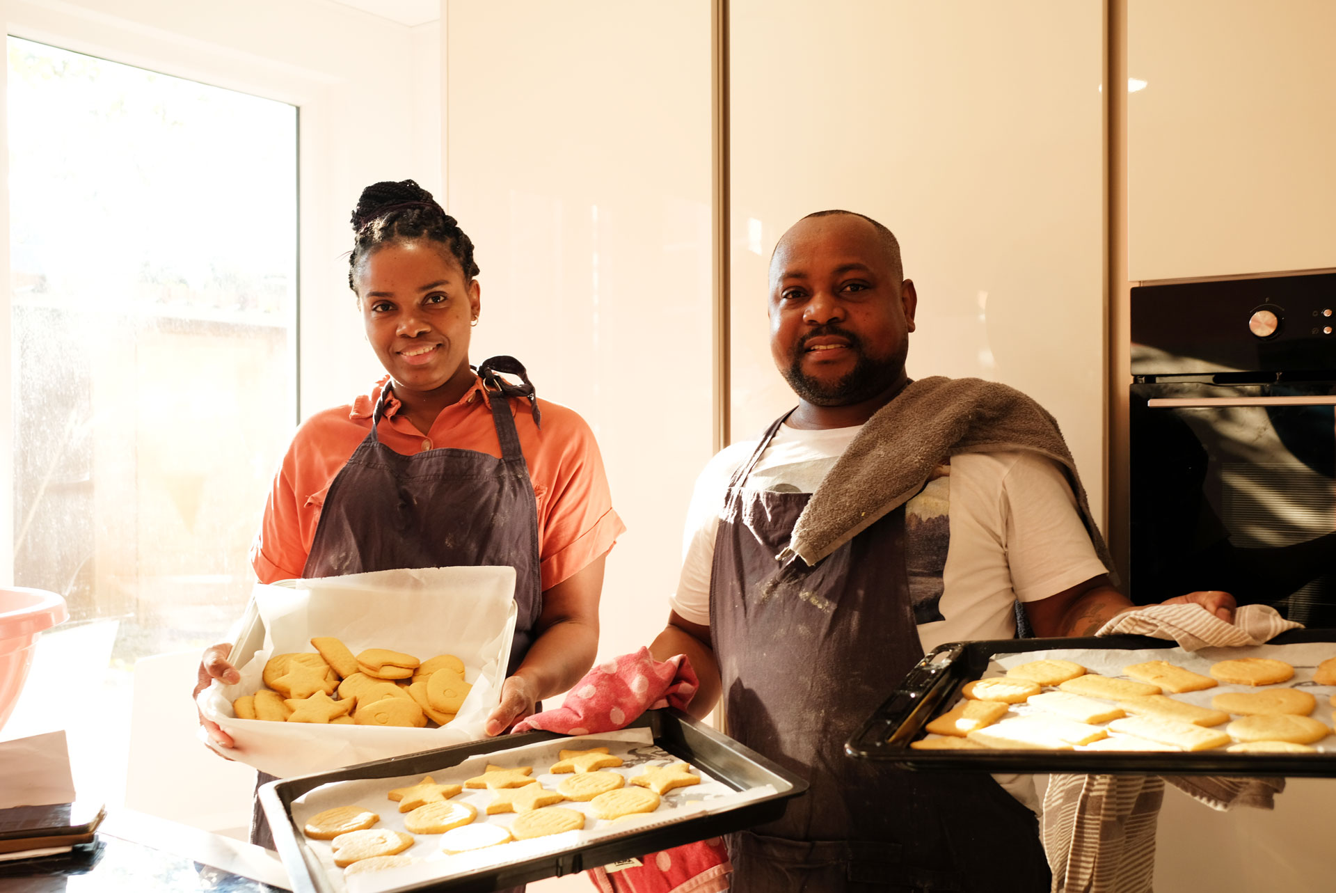 Two people in a kitchen baking cookies.