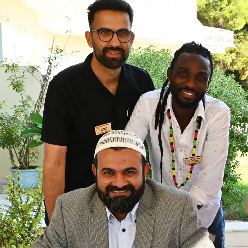 Three men from different part of the world smiling and looking straight into the camera.